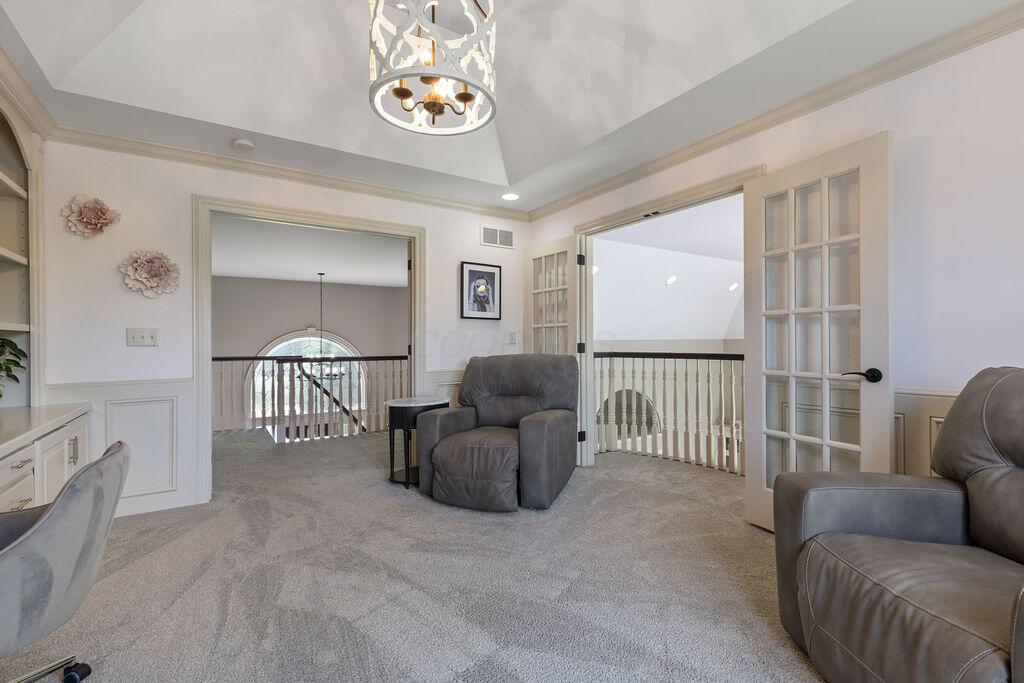 2570 Jewett Road Powell, OH 43065 - Photo 46 of 104 • Grey carpet • Pink painted & wainscoted walls • Built-in bookcases • Tray ceiling • Chandelier • French doors to Juliet balcony • French doors to composite deck