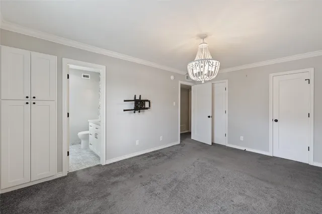 a view of an empty room and hallway with chandelier