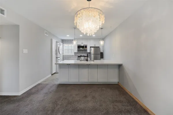an empty room with kitchen view and stainless steel appliances