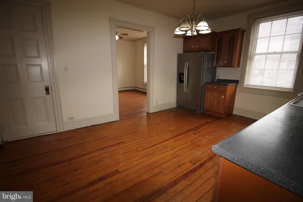 a view of a livingroom with wooden floor and kitchen space