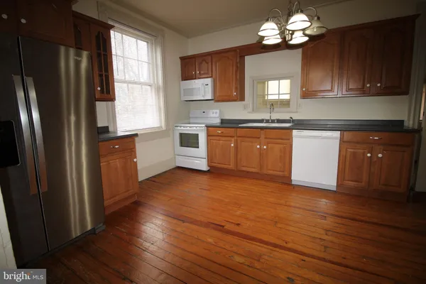 a kitchen with granite countertop wooden floors stainless steel appliances a sink and a window
