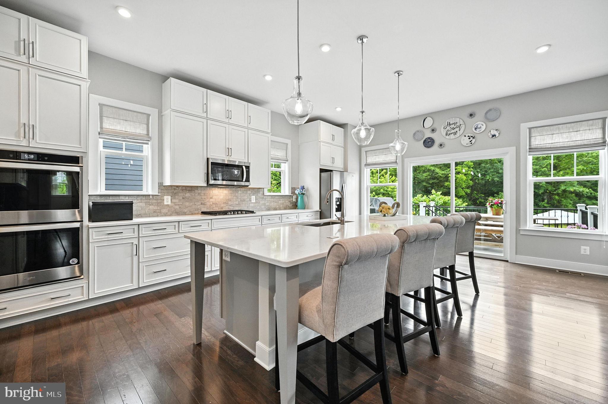 40960 River Cane Place Aldie, VA 20105 - Photo 8 of 54 a kitchen with stainless steel appliances granite countertop a stove a sink a microwave a refrigerator a dining table and chairs with wooden floor