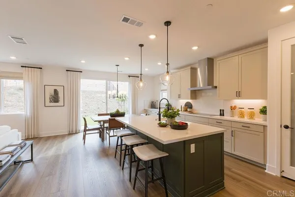 a kitchen with a dining table chairs wooden floor appliances and cabinets