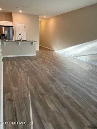 a view of kitchen and empty room with wooden floor