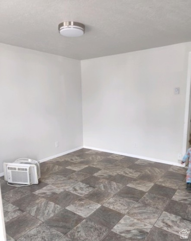 590 Pilot Avenue Wendover, UT 84083 - Photo 11 of 20 Empty room featuring a wall unit AC, dark stone finish flooring, and a textured ceiling