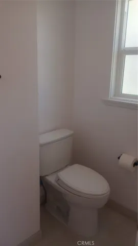 a white toilet sitting in a bathroom next to a window