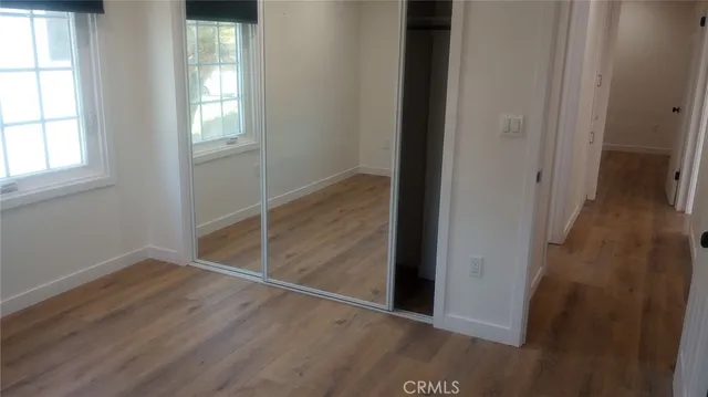 an empty room with wooden floor closet and windows