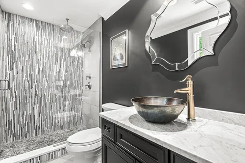 a bathroom with a granite countertop sink toilet a mirror and shower curtain
