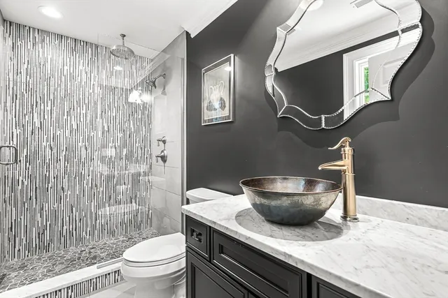 a bathroom with a granite countertop sink toilet a mirror and shower curtain