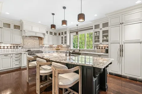 a kitchen with stainless steel appliances granite countertop a table chairs stove and kitchen island