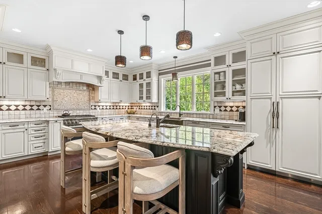 a kitchen with stainless steel appliances granite countertop a table chairs stove and kitchen island
