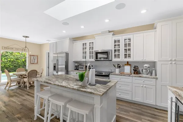 a kitchen with stainless steel appliances granite countertop a stove top oven a sink dishwasher a dining table and chairs with white cabinets