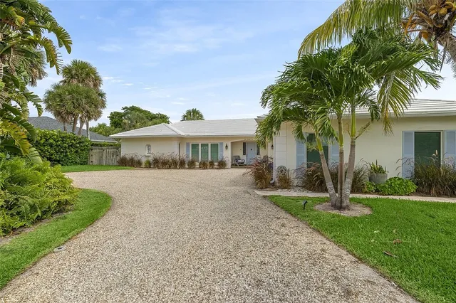 a front view of a house with garden and trees