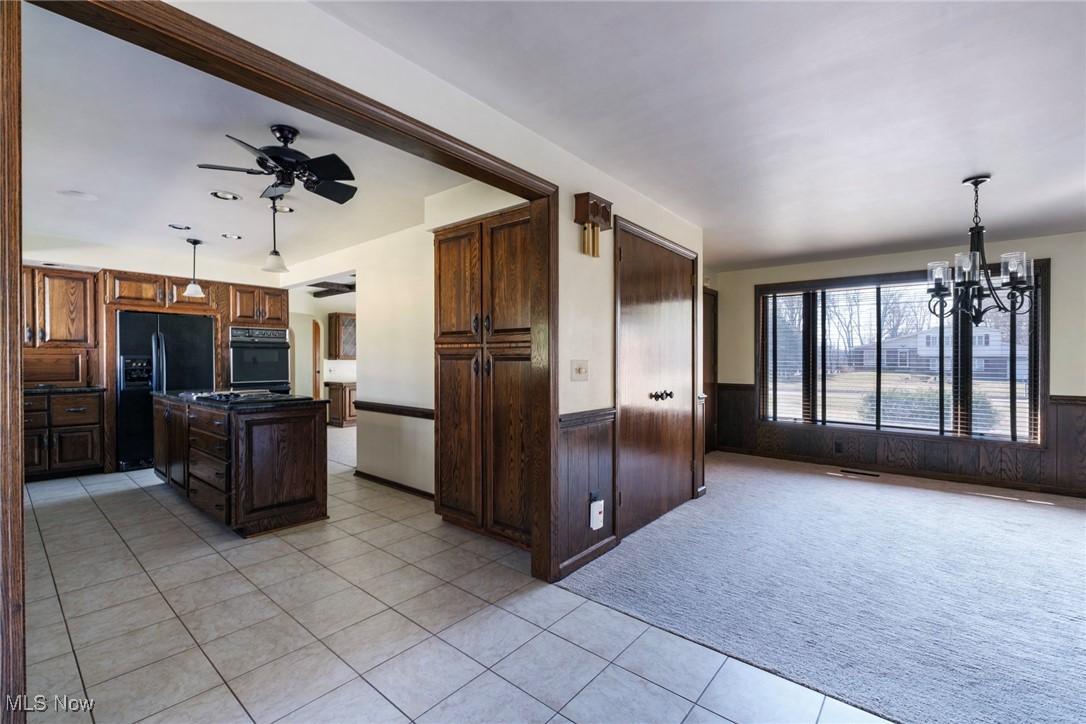 7059 Stewart Sharon Road Hubbard, OH 44425 - Photo 23 of 49 Kitchen with a wainscoted wall, a kitchen island, black appliances, ceiling fan with notable chandelier, and light colored carpet