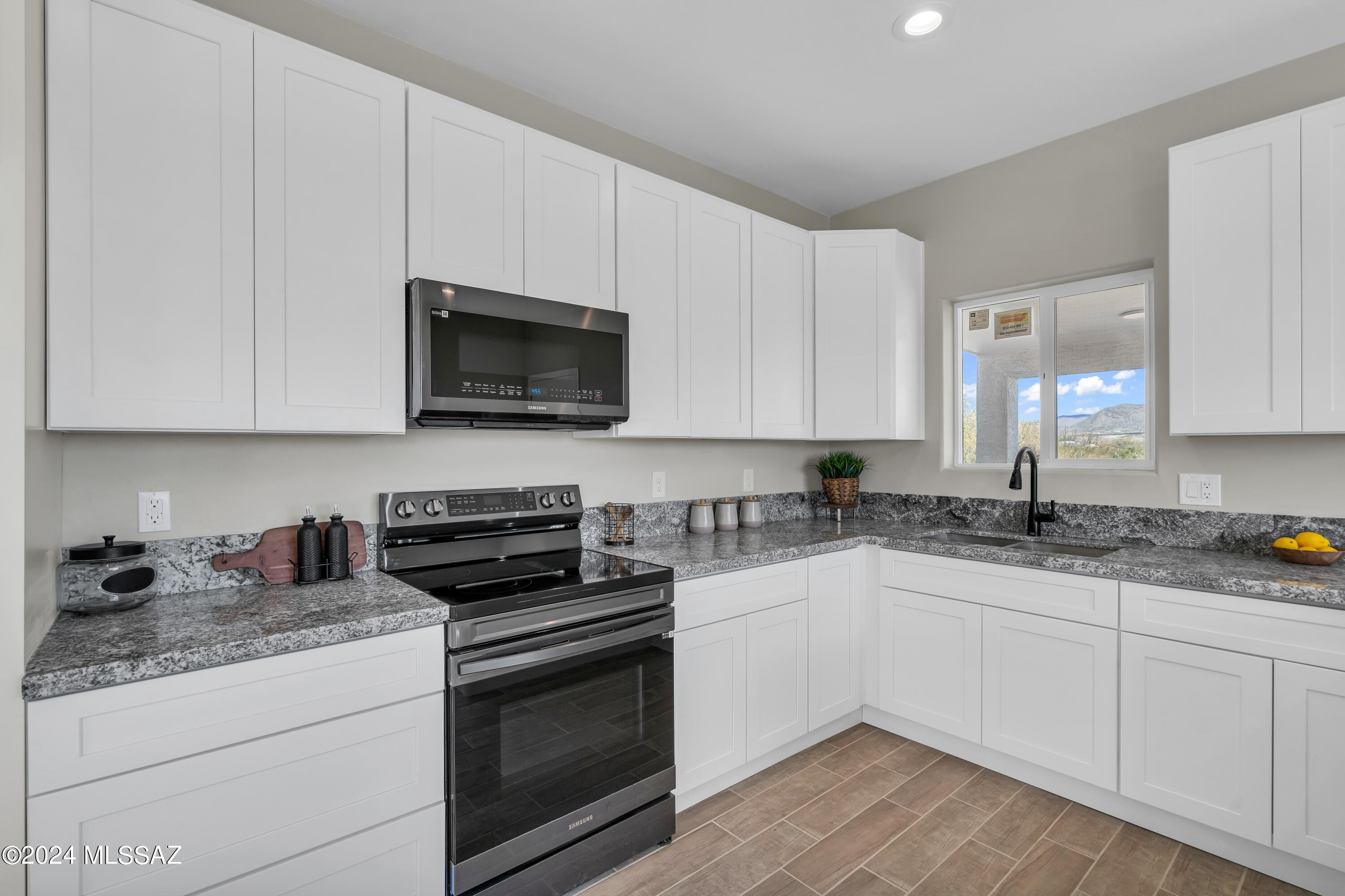 103 Headge Court Rio Rico, AZ 85648 - Photo 6 of 35 a kitchen with granite countertop white cabinets and white appliances