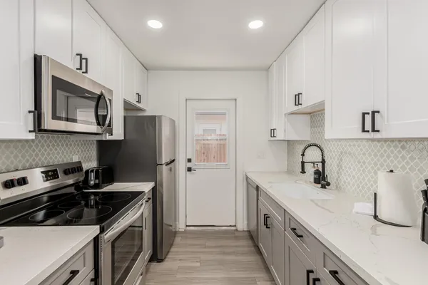 a kitchen with stainless steel appliances granite countertop a sink stove microwave and refrigerator
