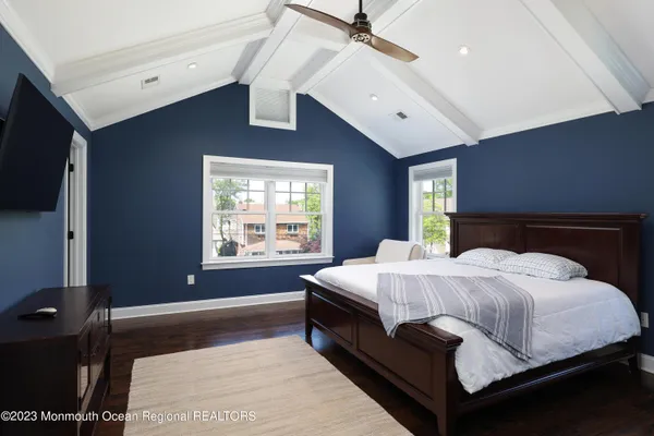 a spacious bedroom with a large bed and a flat tv screen on dresser