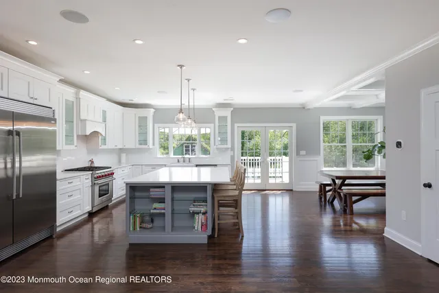 a kitchen with stainless steel appliances granite countertop a stove top oven a refrigerator a dining table and chairs with wooden floor