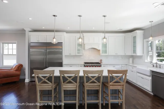 a kitchen with stainless steel appliances kitchen island granite countertop a dining table chairs and white cabinets