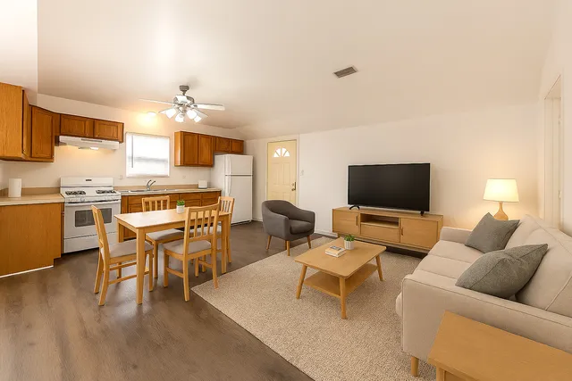 a living room with furniture kitchen view and a flat screen tv