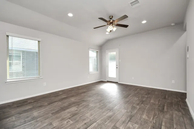an empty room with wooden floor and windows