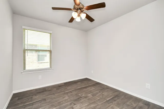 an empty room with wooden floor and ceiling fan