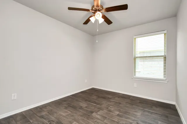 an empty room with wooden floor closet and windows