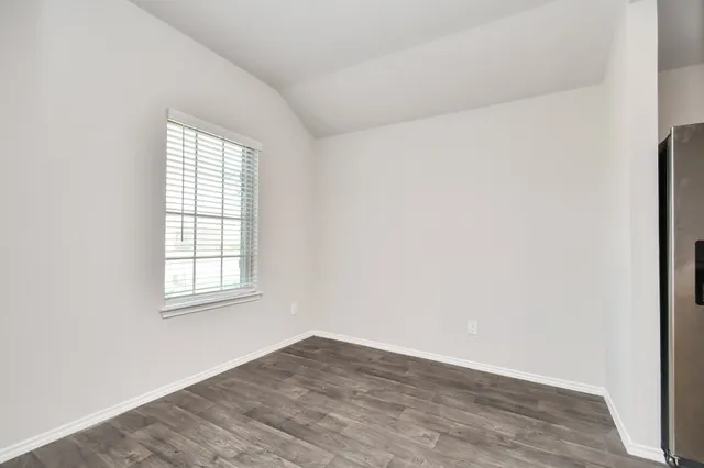 a view of a hallway with wooden floor and a bathroom