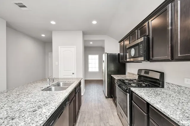 a kitchen with stainless steel appliances kitchen island granite countertop a stove a sink and a refrigerator