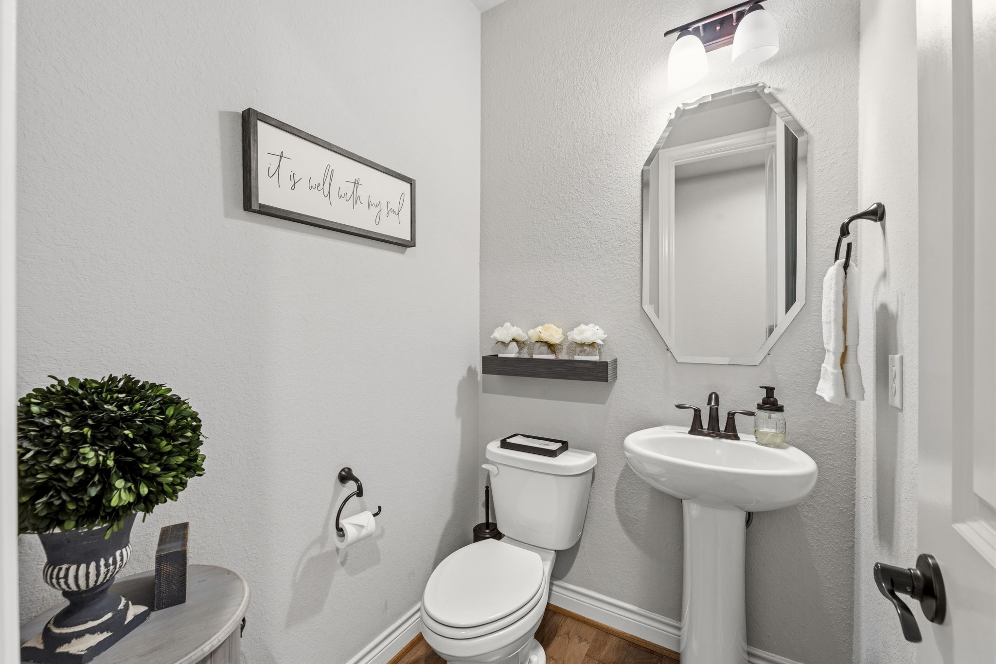 14012 Beartooth Bend Trail Conroe, TX 77384 - Photo 28 of 50 Half bath for guests includes wood flooring, pedestal sink, toilet, and an octagon beveled mirror.
