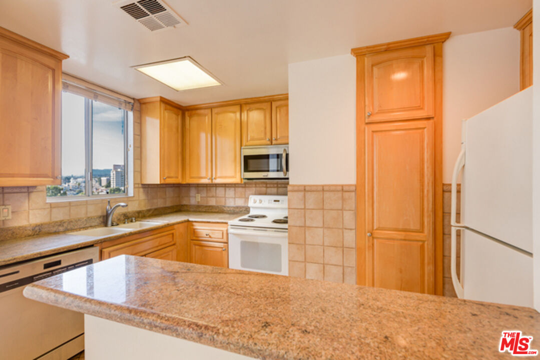 10747 Wilshire Boulevard, Unit 905 Los Angeles, CA 90024 - Photo 1 of 7 a kitchen with stainless steel appliances granite countertop a sink stove and refrigerator