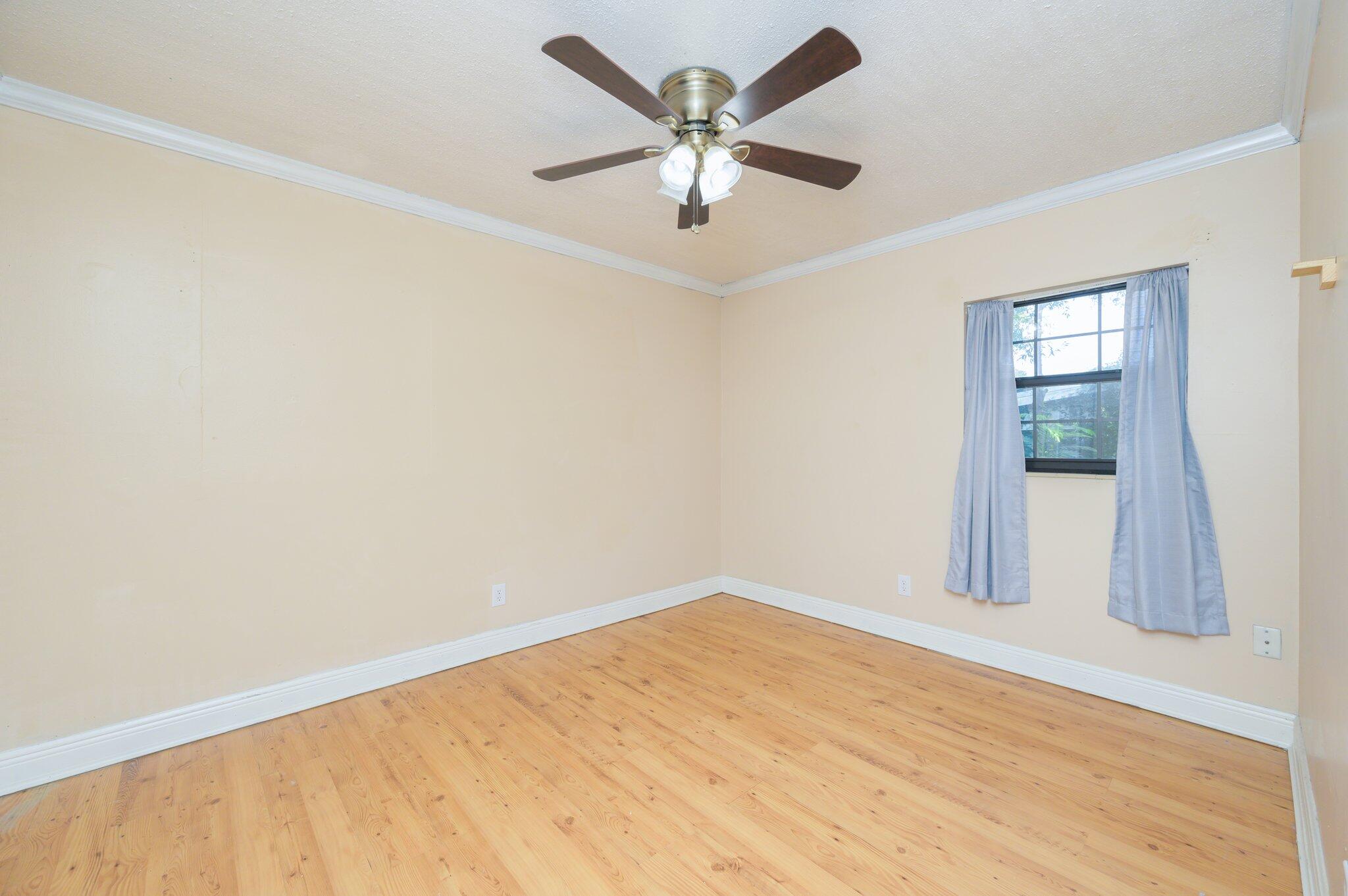 111 Sikes Drive Crestview, FL 32539 - Photo 26 of 46 an empty room with a ceiling fan and wooden floor