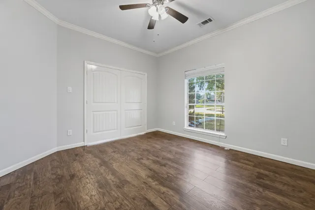 a view of an empty room with wooden floor and a window