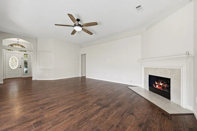 a view of an empty room with wooden floor fireplace and a window