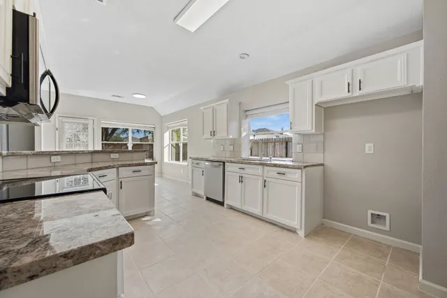 a kitchen with white cabinets and sink
