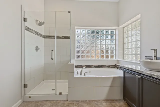 a bathroom with a granite countertop sink a large mirror and a bathtub