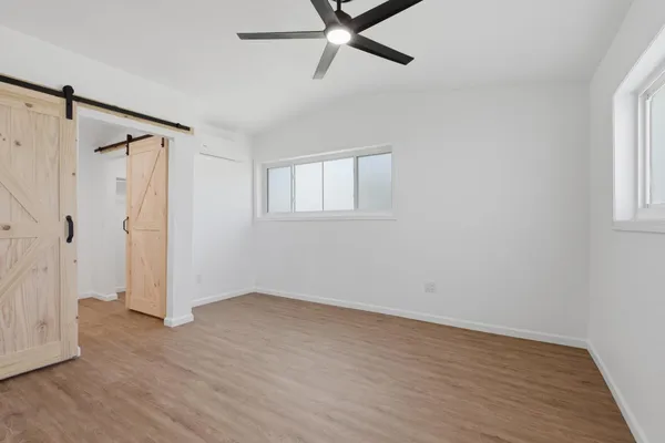 an empty room with wooden floor and windows