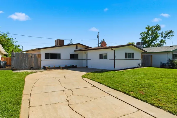 a front view of house with yard and trees in the background