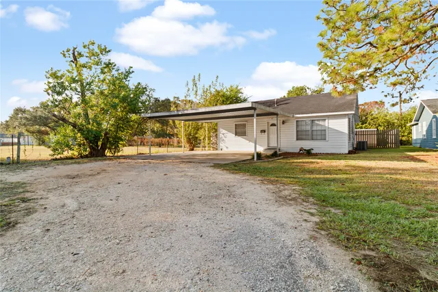 a view of a house with a big yard and large trees