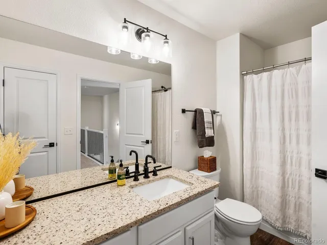 a bathroom with a granite countertop sink a toilet and shower