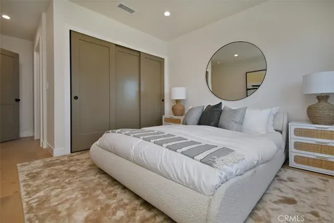 a bedroom with a bed a mirror on dresser and a window