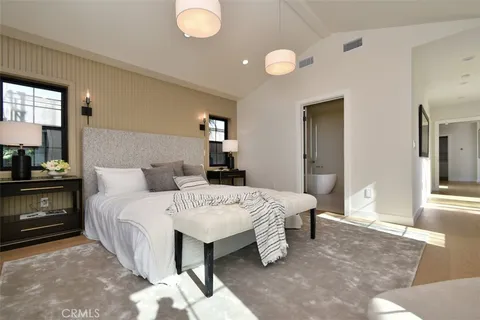 a spacious bedroom with a bed a dresser and chair