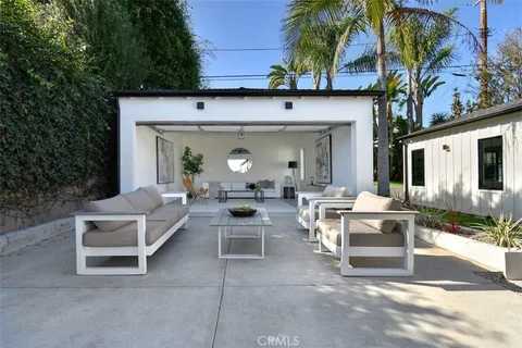 a view of a patio with couches table and chairs under an umbrella