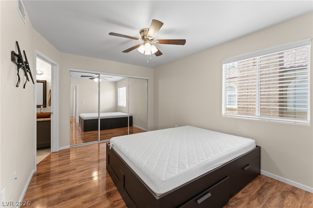7950 West Flamingo Road, Unit 2142 Las Vegas, NV 89147 - Photo 18 of 24 Hardwood flooring gleams in this bedroom, featuring a large window and convenient mirrored closet doors.