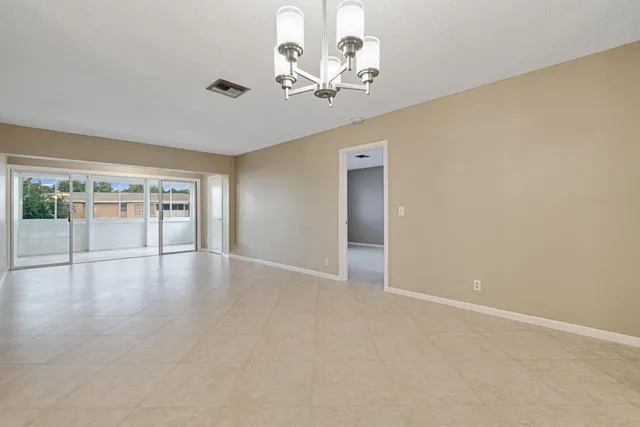 an empty room with chandelier fan and windows