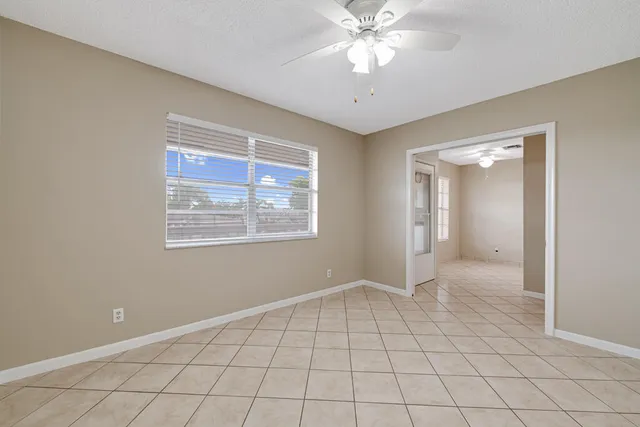 a view of an empty room with window and chandelier fan