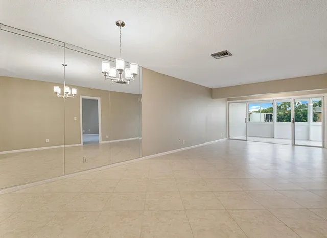an empty room with chandelier fan and windows