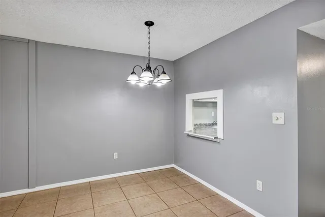 a view of a hallway with chandelier and refrigerator