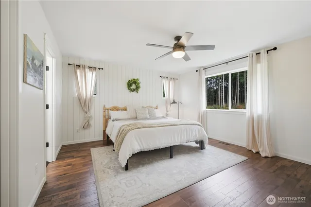 a spacious bedroom with a bed and wooden floor
