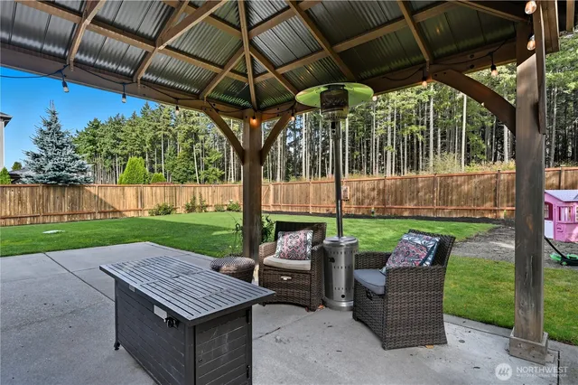 a view of a patio with table and chairs under an umbrella with a small yard